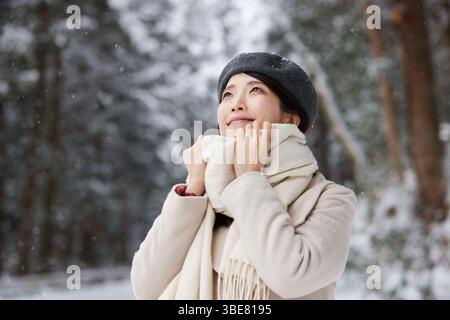 Donna giapponese che indossa una sciarpa in piedi in un paese innevato in inverno Foto Stock