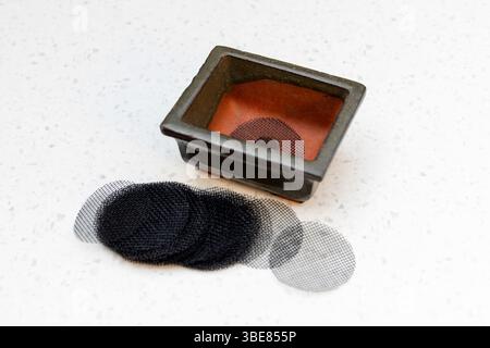 Rete rotonda per coprire il foro di drenaggio e il vaso di bonsai rettangolare su sfondo bianco isolato Foto Stock