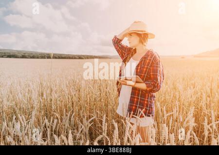 Donna campo di grano. Agronomo, agricoltore donna che controlla i picchi d'orzo maturo dorato nel campo coltivato. Primo piano della mano femminile sulla piantagione in agricoltura Foto Stock