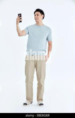 Un giovane che fissa il suo schermo del telefono, assolutamente entusiasta con il braccio alzato in alto Foto Stock