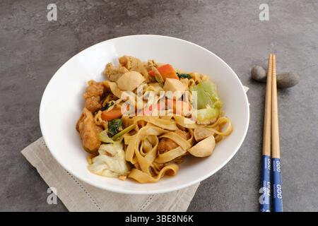 Kwetiaw o Kwetiau, spaghetti di riso fritti con polpette e verdure. Popolare in Indonesia Foto Stock