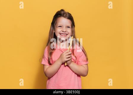 Una ragazza felice tiene uno spazzolino tra le mani. Un colpo isolato. Odontoiatria pediatrica Foto Stock