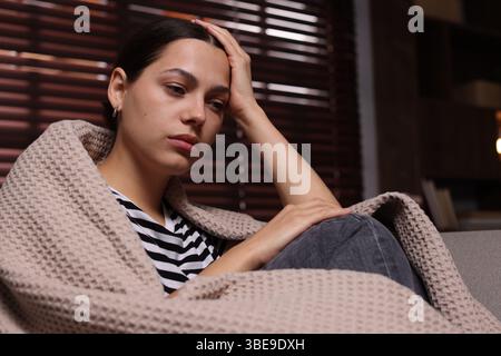 Donna depressa avvolta in plaid a casa Foto Stock
