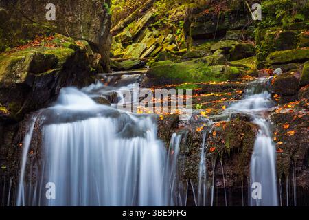 Paesaggio con cascata nella gola rocciosa e foresta con acqua blu che cade in uno stagno blu e con dintorni rocciosi nella Repubblica Ceca Europa Foto Stock