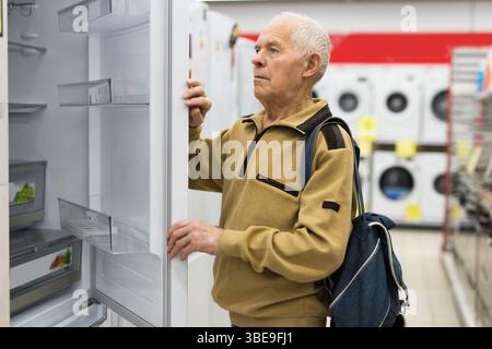 Pensionato Senor MAN che acquista un frigorifero nello showroom del negozio di elettrodomestici Foto Stock
