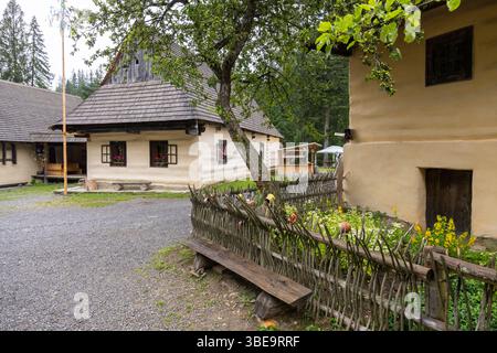 Case tradizionali slovacche con recinzione in legno e fiori nel museo all'aperto di Zuberec, Slovacchia Foto Stock