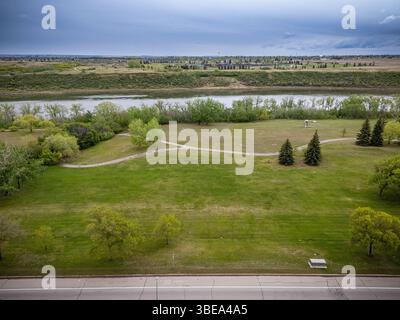 Grande campo aperto con un fiume che lo attraversa. Il cielo è nuvoloso e l'erba è verde Foto Stock