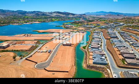 Il sito di costruzione di Aerial Suburban Homes vicino a Lake and Mountains Fly Over Foto Stock