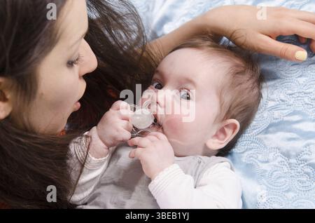 Mamma e sei mesi di figlia felicemente distesi sul lettino Foto Stock