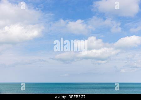 Un tranquillo scenario oceanico caratterizzato da vivide acque turchesi e nuvole bianche sparse in un cielo blu limpido, evocando sentimenti di pace e relax. Natura Foto Stock