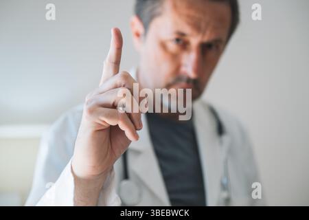 Avvertimento medico, ritratto di adulto adulto adulto adulto adulto medico professionale con dito indice sollevato, fuoco selettivo Foto Stock