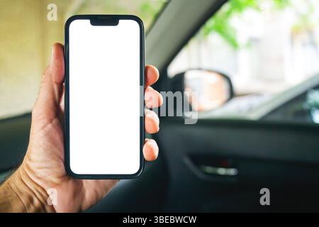 Conducente di auto che tiene lo smartphone con uno schermo nero all'interno del veicolo, messa a fuoco selettiva Foto Stock