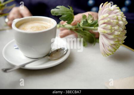 tazza di caffè con latte accanto al fiore Foto Stock