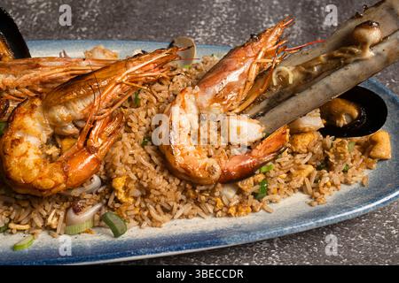 Riso fritto a base di pesce con gamberetti e cozze alla griglia, servito su un piatto blu Foto Stock
