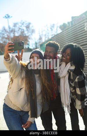 Tre allegri studenti multietnici si fanno un selfie insieme in una giornata invernale all'aperto Foto Stock