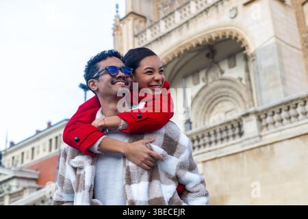 Giovani coppie sorridenti e abbracciate mentre visitano una storica città europea durante le loro vacanze Foto Stock