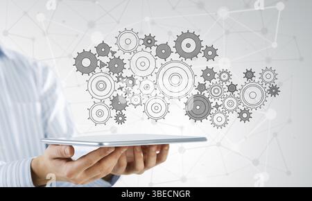 Vista ravvicinata di imprenditore che mostra un tablet pc con ingranaggi sullo schermo Foto Stock