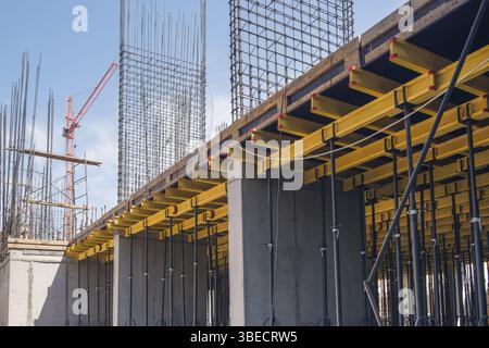 Strutture in cemento armato dell'edificio in costruzione. ponteggi e supporto. gru da cantiere Foto Stock