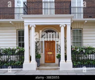 Ingresso all'elegante vecchia casa cittadina di Londra con piantatrici su ringhiera di ferro Foto Stock