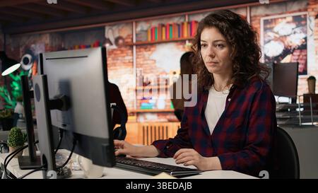 Dipendente che lavora in un ufficio startup innovativo utilizzando linguaggi di programmazione per creare applicazioni. Agenzia di sviluppo software specializzata IN IT che ottimizza il codice, digita sulla tastiera del computer, fotocamera A. Foto Stock