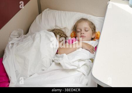 Due bambini dormono sul treno sullo stesso punto di massa nella seconda classe carro abitacolo Foto Stock
