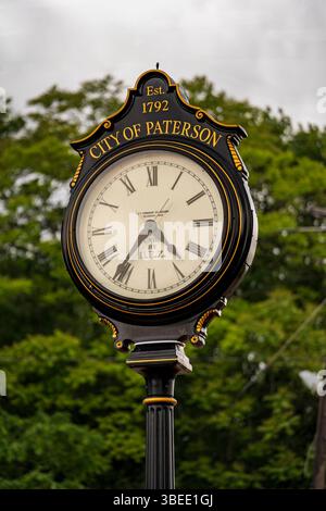 Paterson, New Jersey - USA - 24 maggio 2025 Orologio da strada decorato nero e oro a Paterson, New Jersey, mostra le 4:35. Adagiato su lussureggianti alberi verdi, afferma con orgoglio "città Foto Stock