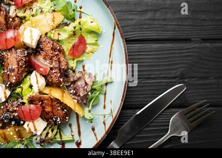 Squisita insalata con pera caramellata, fegato alla griglia, gorgonzola, uva succosa, aceto balsamico e verdure fresche. Presentazione elegante. Concep Foto Stock