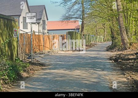 Vista in primavera, tranquilla corsia di campagna a binario singolo, nuove recinzioni e case in costruzione su terreni agricoli, parte di una tenuta con recinzione a15 a Doddinghurst, Essex, Inghilterra, Regno Unito Foto Stock