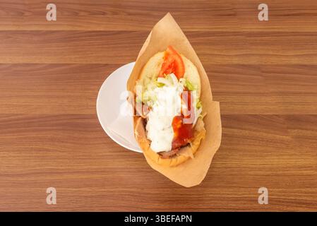 Tipico sandwich kebab con salse e verdure su un piatto bianco economico Foto Stock