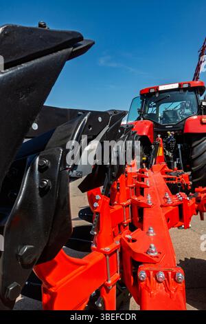 Immagine ravvicinata di un moderno trattore rosso e dell'attrezzatura agricola nera. Foto Stock