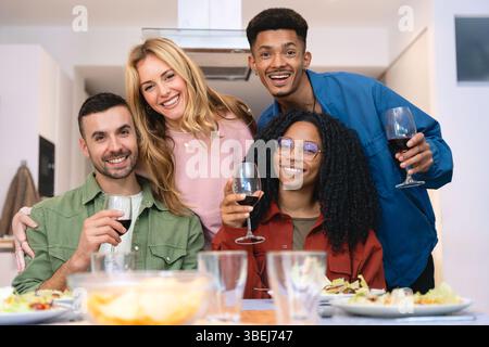 Gruppo multietnico di amici felici che brindano con vino rosso in allegria Foto Stock