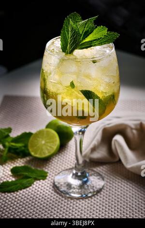 Cocktail Mojito con ghiaccio, menta e contorno lime su un tavolo moderno, primo piano Foto Stock
