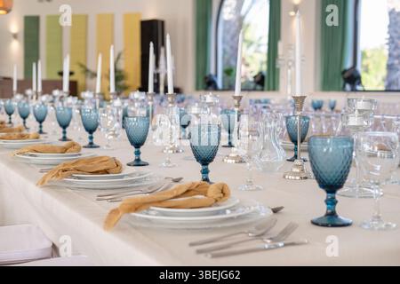 Tavolo da banchetto formale pronto per un evento o un matrimonio con piatti bianchi e di vetro a strati, posate d'argento, tovaglioli e bicchieri eleganti Foto Stock