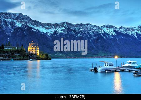 Montagne innevate sul castello di Seeburg a Iseltwald sul lago di Brienz (Brienzersee) di notte, Svizzera Foto Stock