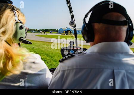 Interni in elicottero all'aeroporto regionale di Brockville con pilota maschio e passeggero donna con gabbie in primo piano Foto Stock