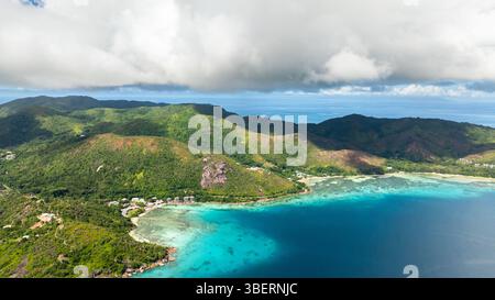 Lussureggianti colline verdi incontrano spiagge di sabbia bianca e acque turchesi cristalline. Curieuse, Seychelles. Foto Stock