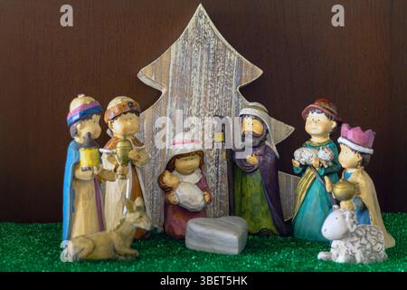 Figure in stile bambino del presepe con un albero di Natale in legno sullo sfondo Foto Stock