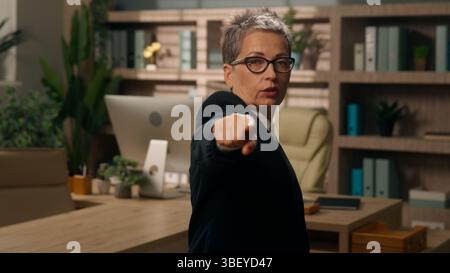 Una vecchia donna d'affari caucasica che ti indica con l'indice un serio responsabile delle risorse umane che si occupa di reclutare un responsabile scelga di presentarlo di fronte alla mano che guarda la fotocamera in ufficio Foto Stock