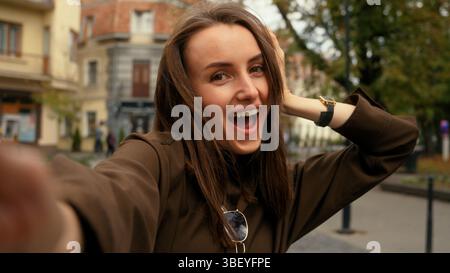 Videocamera per telefono cellulare Guarda felice sorridente donna caucasica in posa sorridente fai selfie con la ragazza di strada in città che detiene il record di videochiamata su smartphone Foto Stock