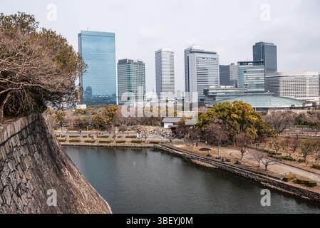 Affacciato sul fossato delle caste di fronte allo skyline del Parco finanziario di Osaka. Castello di Osaka, Osaka, Kansai, Giappone Foto Stock