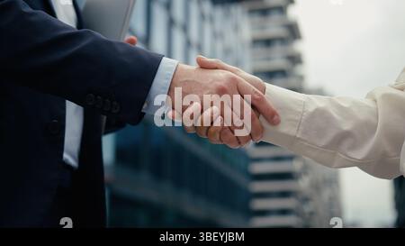 Due uomini d'affari che stringono la mano incontrano un uomo d'affari in città stringono la mano con una donna d'affari partner diversità multirazziale stringendo le mani uomo di cooperazione Foto Stock