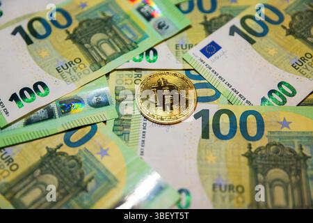 Moneta in criptovaluta bitcoin d'oro su banconote da 100 euro. Foto Stock