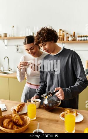 Una coppia dolce si diverte a trascorrere la domenica mattina a casa preparando la colazione e sorseggiando un caffè. Foto Stock