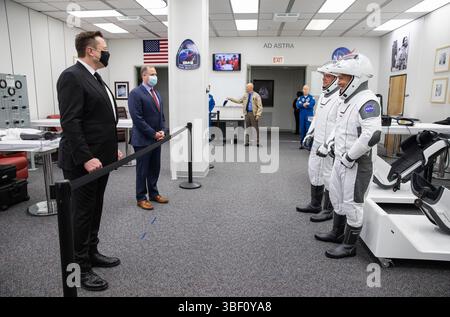Dietro la corda, il CEO e Chief Designer di SpaceX Elon Musk (a sinistra) e l'amministratore della NASA Jim Bridenstine salutano gli astronauti della NASA Robert Behnken (a sinistra) e Douglas Hurley all'interno degli Astronaut Crew Quarters. Foto di Kim Shiflett, NASA maggio 2020 Foto Stock
