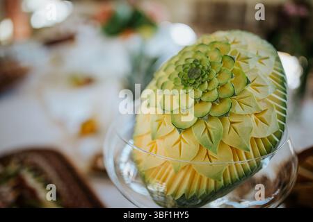 Una foto ravvicinata di un cocomero splendidamente intagliato collocato in una ciotola di vetro. L'anguria è stata intagliata con un motivo floreale, creando Foto Stock