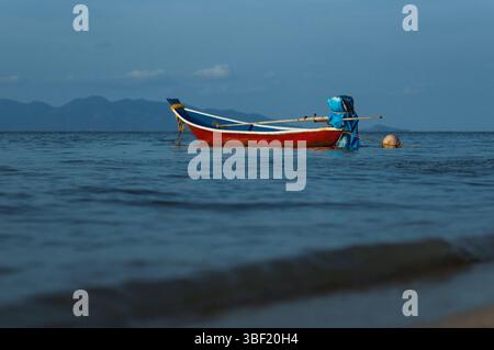 Barca da pesca rossa solitaria che galleggia sul mare calmo Foto Stock