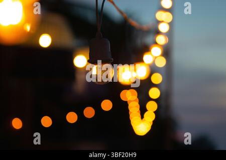 Luci a corda accese in un bokeh da sogno al crepuscolo Foto Stock