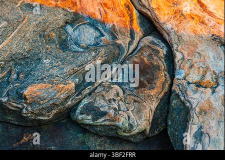 Lungo la costa svedese, la luce del sole proietta un caldo bagliore sulle aspre scogliere, rivelando intricati motivi nelle rocce mentre il giorno passa nella notte, Foto Stock
