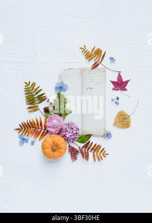 Un piatto floreale di natura morta autunnale con fiori, foglie, vecchia pagina vintage, su sfondo bianco di tela, con spazio vuoto per scrivere Foto Stock