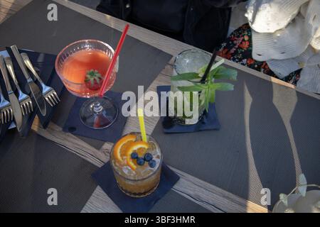 Bicchieri da cocktail seduti al tavolo della cucina - Amarretto sours, daquari alla fragola e Mojito. Foto Stock